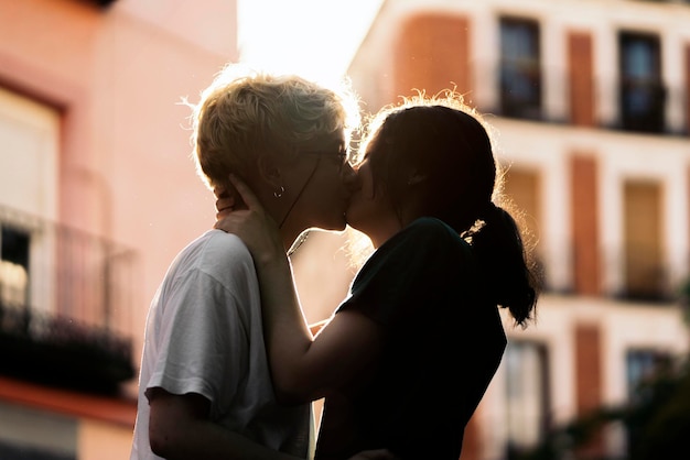 Foto di stock di una vista laterale di una giovane coppia lesbica che si bacia per strada C'è una retroilluminazione