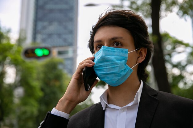 Foto di stock di uomini che parlano al telefono cellulare per strada indossa una maschera protettiva per la prevenzione di un virus