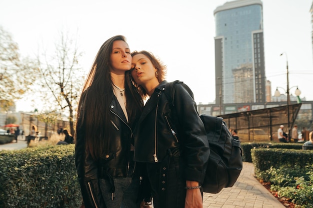 Foto di strada di amiche attraenti al tramonto che posano sulla fotocamera indossando abiti casual