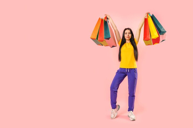 Foto di tutto il corpo di una giovane donna attraente felice sorriso positivo tenere borse della spesa comprare vendita isolato su sfondo di colore rosa