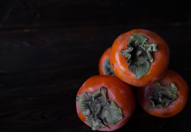 Foto di un cachi su sfondo scuro Frutta su sfondo in legno Foto di alta qualità