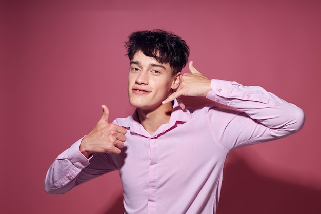 Foto di un giovane ragazzo romantico con una camicia rosa che gesticola con le mani lo stile di vita inalterato