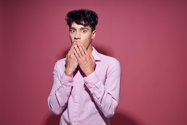 Foto di un giovane ragazzo romantico con una camicia rosa che gesticola con le mani lo stile di vita inalterato