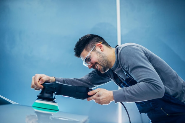 Foto di un giovane sorridente che lucida un'auto.