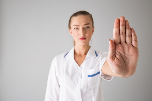 Foto di un medico cosmetologo giovane e bella donna isolato sopra il muro grigio che mostra il gesto di arresto.