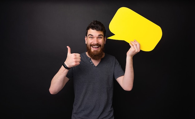 Foto di un ragazzo barbuto che mostra il pollice in su e tiene in mano un fumetto giallo