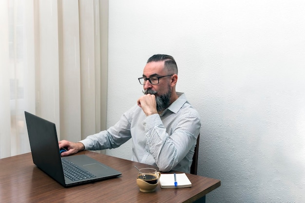 Foto di un uomo barbuto hipster che lavora con il computer portatile a casa