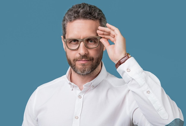 Foto di un uomo maturo con problemi di vista con gli occhiali La vista di un uomo isolato sullo sfondo blu L'uomo maturo con la vista in studio