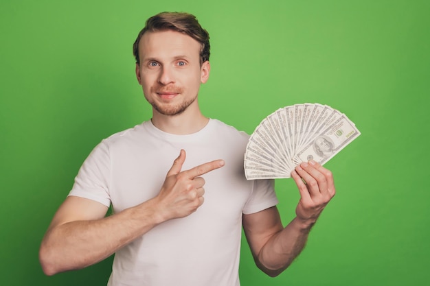 Foto di un uomo ricco e ricco che tiene in mano un fan di contanti che indossa una maglietta bianca su uno sfondo di colore verde