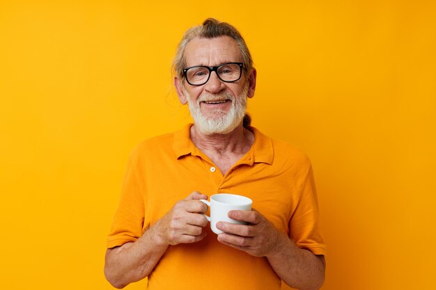Foto di un vecchio pensionato in una maglietta gialla bianca con una tazza in bianco e nero
