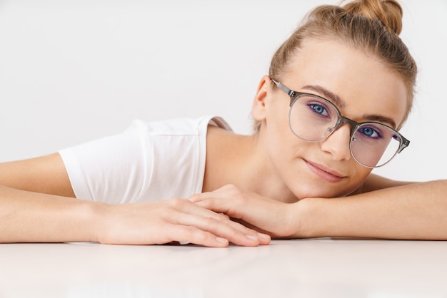 Foto di una bella donna contenta con gli occhiali che guarda la telecamera mentre si appoggia sul tavolo