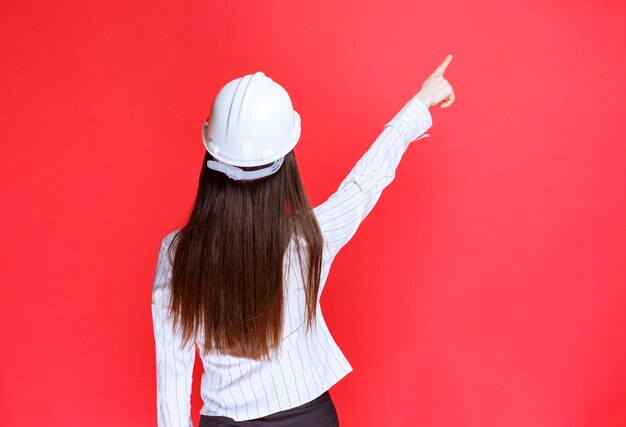 Foto di una bella donna d'affari che indossa il cappello di sicurezza rivolto verso l'alto.