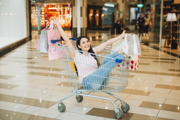 Foto di una bella donna eccitata seduta in un carrello sorridente in un supermercato