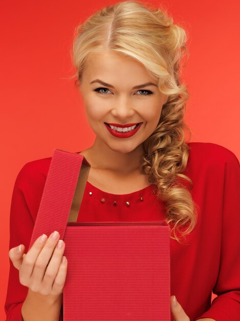 foto di una bella donna vestita di rosso con una confezione regalo aperta