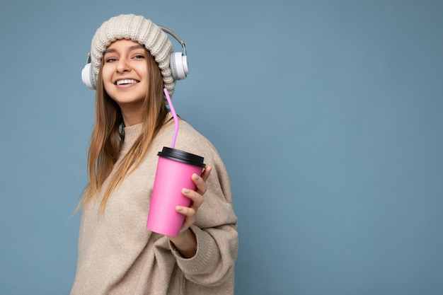 Foto di una bella e gioiosa giovane donna bionda sorridente che indossa un maglione e un cappello invernali beige