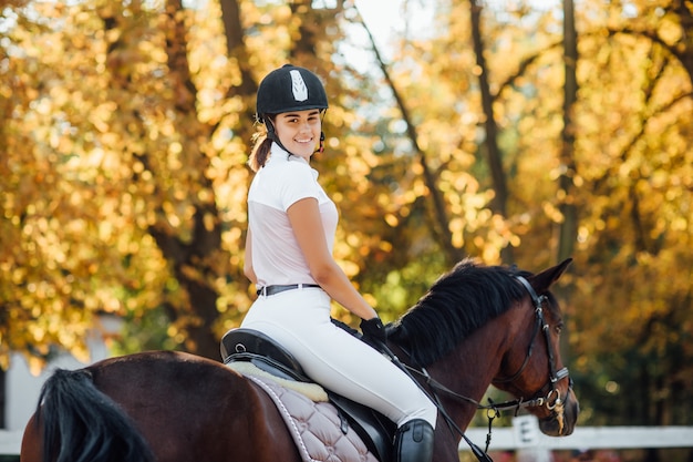 Foto di una bella giovane donna a cavallo con un casco nero e stivali.