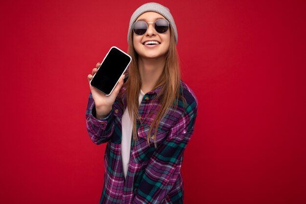 Foto di una bella giovane donna bionda positiva che indossa un'elegante maglietta viola e una maglietta bianca casual