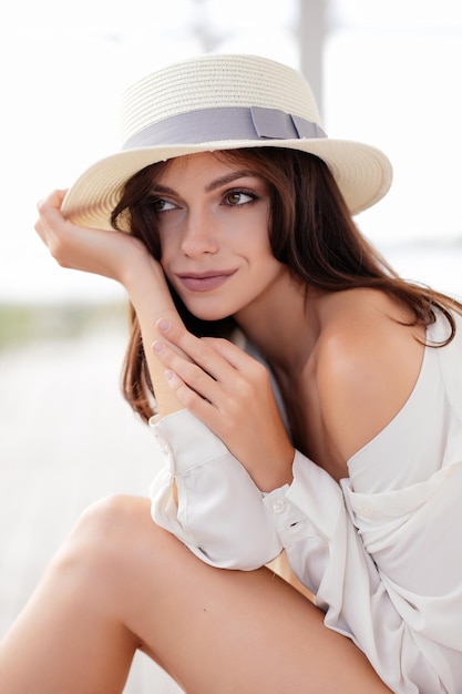 Foto di una bellissima modella in stile boho in costume da bagno bianco sulla spiaggia al tramonto