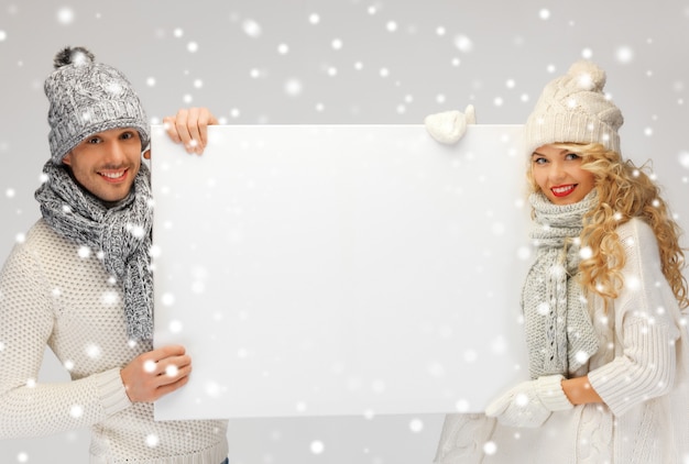 foto di una coppia di famiglia in abiti invernali che tiene una tavola bianca