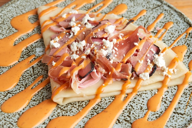 Foto di una deliziosa crepe salata con crema di formaggio prosciutto serrano e salsa chipotle