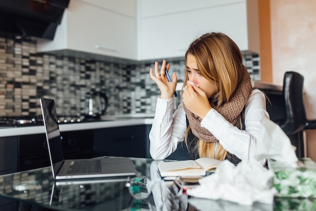 Foto di una donna d'affari preoccupata che tiene in mano i tovaglioli in cucina a casa e usa il laptop