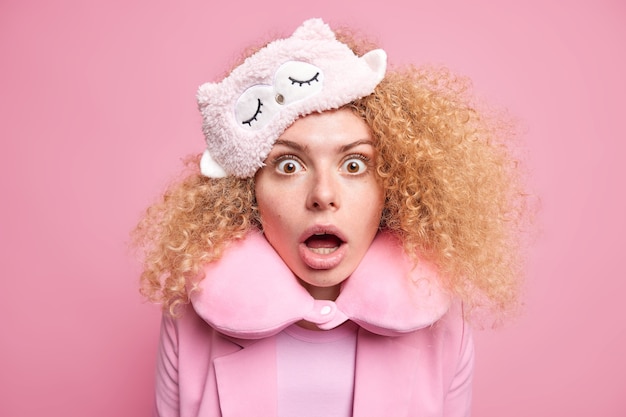 Foto di una donna dai capelli ricci spaventata fissa sorpresa la telecamera