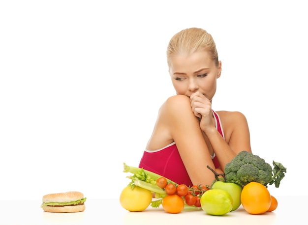 foto di una donna dubbiosa con frutta e hamburger