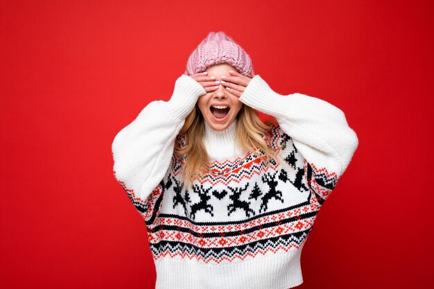 Foto di una giovane bella signora bionda felice positiva con emozioni sincere che indossa un cappello a maglia rosa