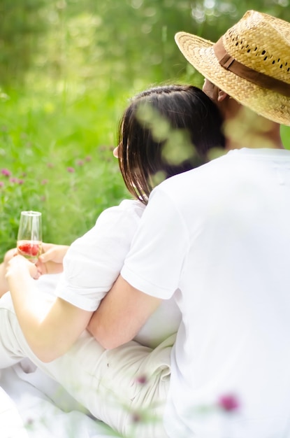 Foto di una giovane coppia che riposa nel campo e si gusta lo champagne