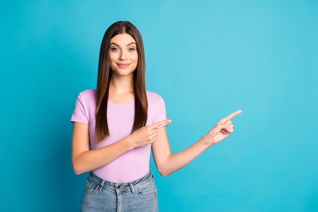 Foto di una giovane donna adorabile vestita in modo casual che punta due braccia con le dita spazio vuoto isolato sfondo di colore blu