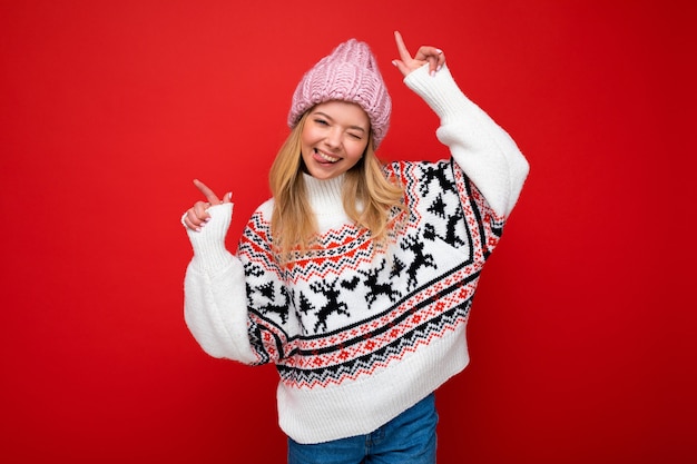 Foto di una giovane donna bionda attraente felice positiva con emozioni sincere che indossa un cappello a maglia rosa