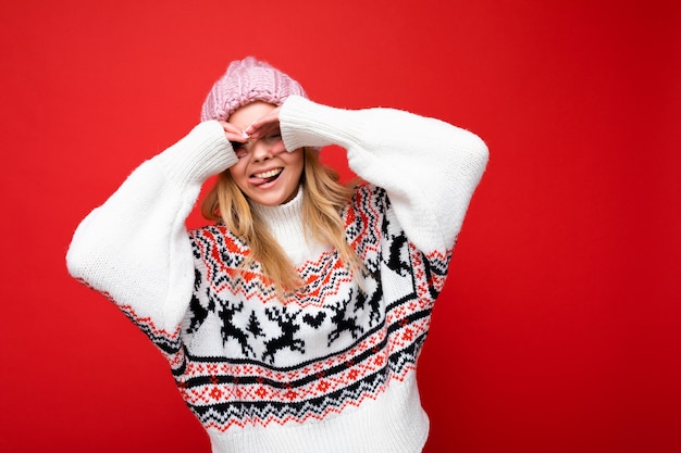 Foto di una giovane donna bionda bella e felice positiva con emozioni sincere che indossa un cappello a maglia rosa