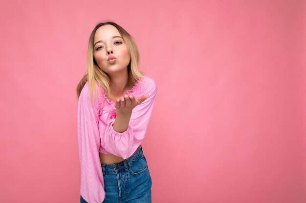 Foto di una giovane donna bionda bella e felice positiva con emozioni sincere che indossa una camicetta rosa