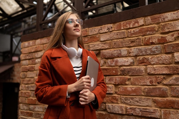 Foto di una giovane donna blogger che cammina per strada con un laptop in mano