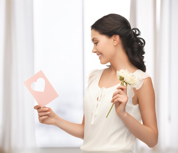 foto di una giovane donna che tiene in mano un fiore e una cartolina