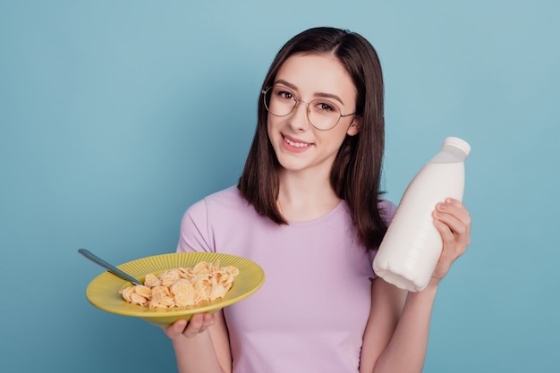 Foto di una giovane donna felice sorriso positivo latte muesli colazione sana dieta isolata su sfondo color verde acqua