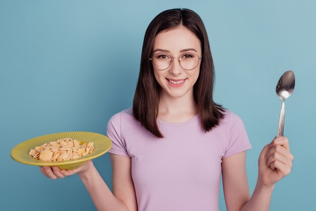 Foto di una giovane donna felice sorriso positivo mangia cornflakes cibo sano colazione isolata su sfondo color verde acqua