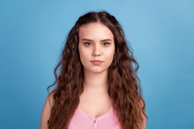 Foto di una giovane donna sicura di sé, capelli ondulati intelligenti, buon umore, indossare abiti casual isolati su uno sfondo di colore blu.