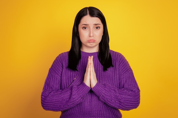 Foto di una giovane ragazza adorabile con i palmi delle braccia insieme chiedere implorare per favore desiderare isolato su uno sfondo di colore giallo