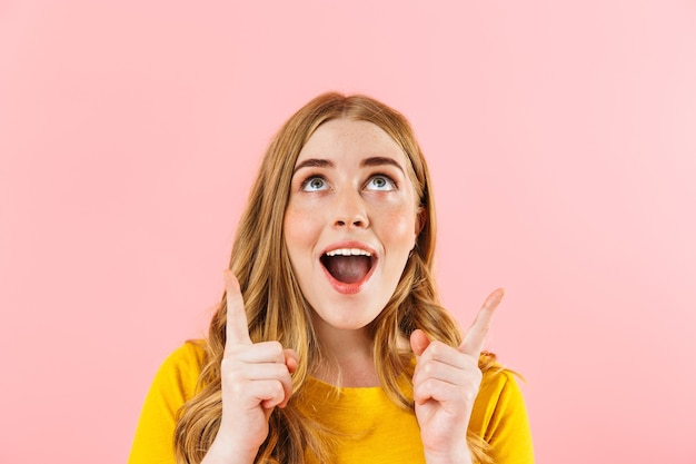 Foto di una giovane ragazza carina emotiva positiva isolata sul muro rosa che mostra copyspace.