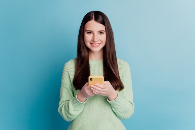 Foto di una giovane ragazza che utilizza smartphone isolato su sfondo blu