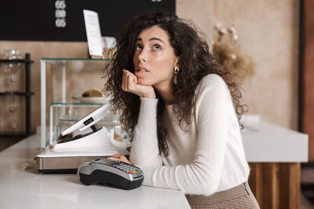 Foto di una ragazza che pensa all'acquirente al bar in piedi vicino al terminal