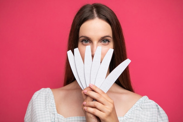 foto di una ragazza che tiene le lime per unghie vicino al viso