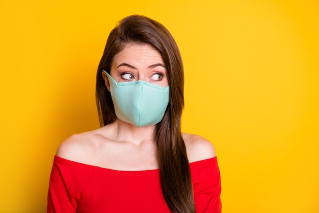 Foto di una ragazza stupita in maschera medica guarda copyspace impressionato quarantena informazioni sull'epidemia di covid indossare top rosso isolato su sfondo brillante brillante