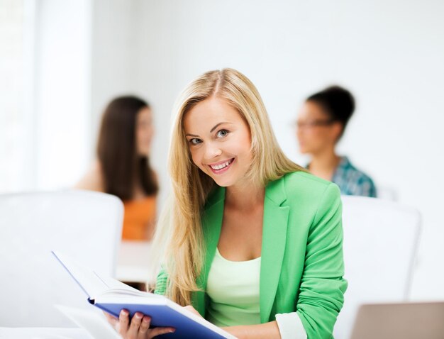 foto di una studentessa sorridente che legge un libro a scuola