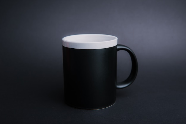 Foto di una tazza nera su oscurità isolata
