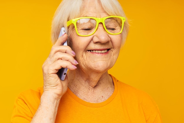 Foto di una vecchia signora in pensione che parla al telefono con le emozioni del primo piano degli occhiali gialli