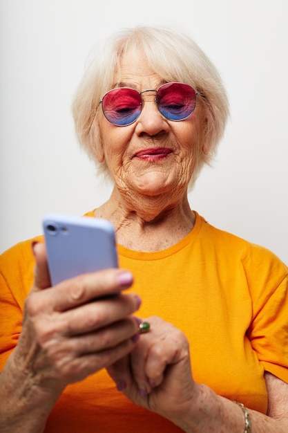 Foto di una vecchia signora in pensione con occhiali da sole casual tshirt che parla al telefono vista ritagliata