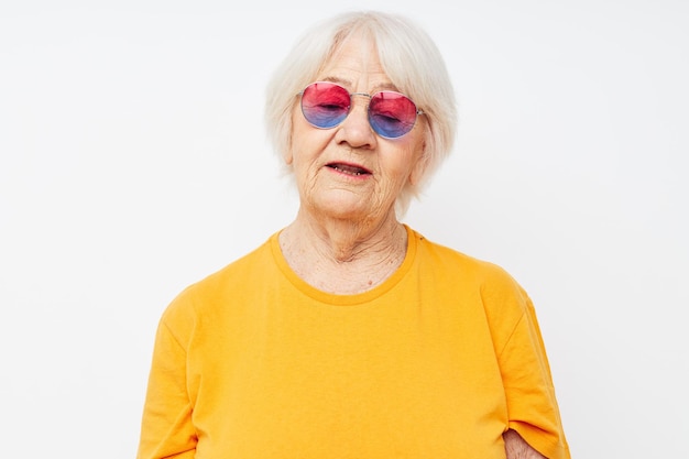 Foto di una vecchia signora in pensione con una maglietta gialla in posa su sfondo chiaro