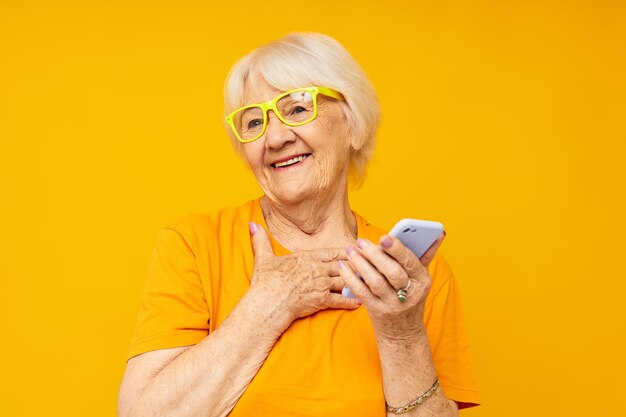 Foto di una vecchia signora in pensione divertente che parla al telefono su sfondo giallo